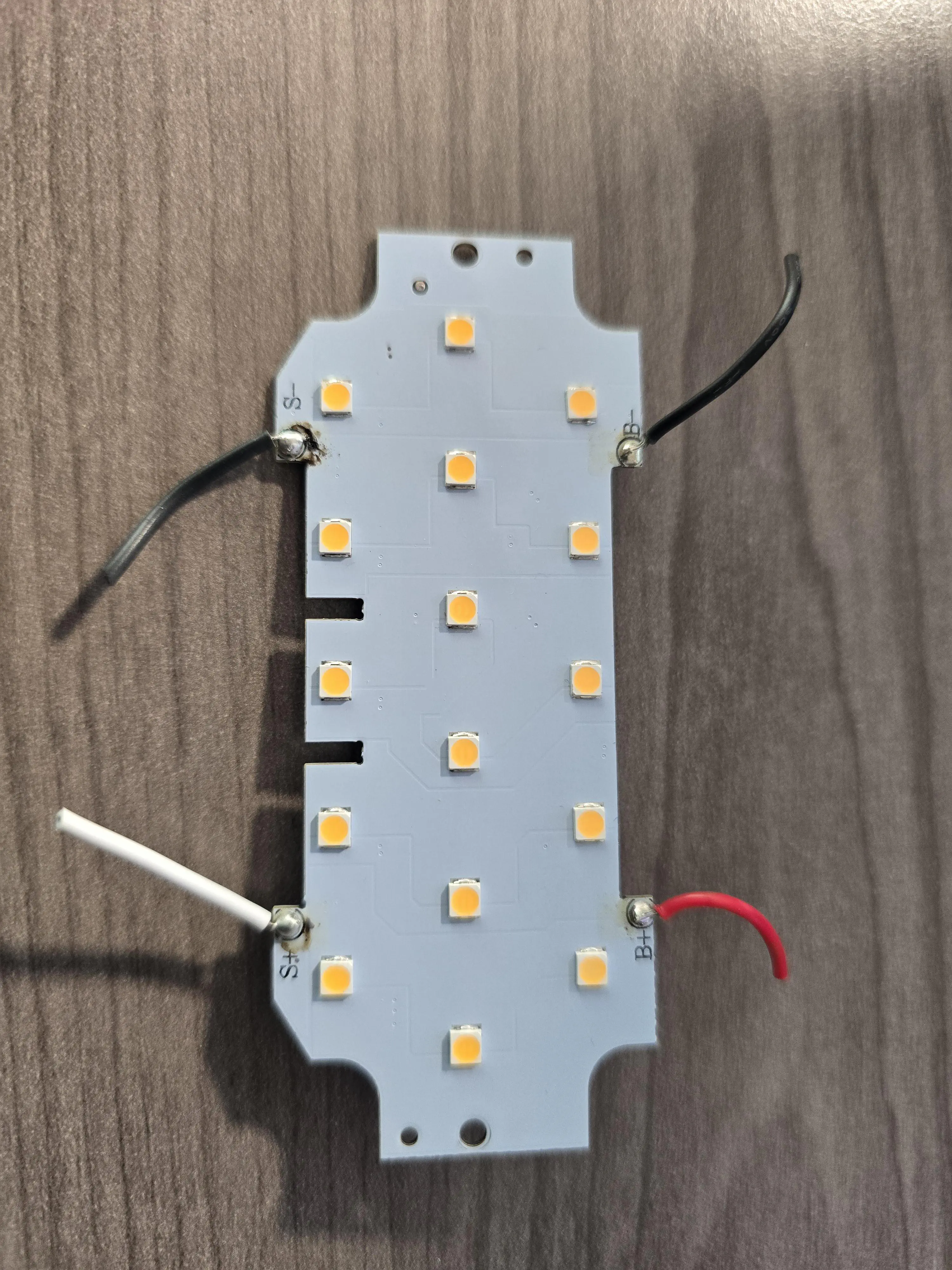LED board with 4 cut wires attached. Black wires are connected to “S-” and “B-”, a white wire is connected to “S+”, and a red wire is connected to “B+”