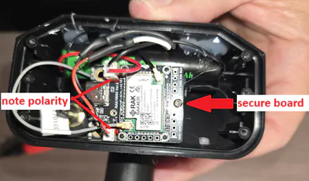Arrows pointing to the screw securing the board to the case, and highlighting the polarity of the power leads